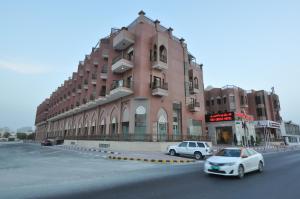 un gran edificio rosa con coches estacionados frente a él en Red Castle Hotel en Sharjah
