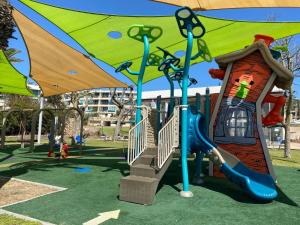 a playground with a slide and an umbrella at Pure Bliss Caesarea - אושר טהור בקיסריה in Caesarea