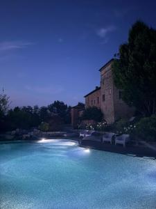 a swimming pool with chairs and a building at night at La Torre Masana in Vigostano