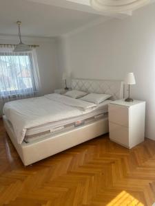 a bedroom with a large white bed and a wooden floor at Grand apartman in Banja Luka