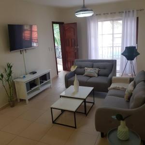 a living room with a couch and a tv at 2BR Condo with Pool, Walk to Beach, Bvaro in Punta Cana
