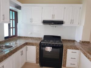 a kitchen with a stove and white cabinets at 2BR Condo with Pool, Walk to Beach, Bvaro in Punta Cana