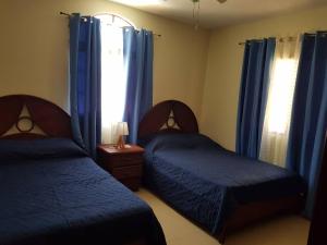 a bedroom with two beds and blue curtains and a window at 2BR Condo with Pool, Walk to Beach, Bvaro in Punta Cana +9 photos