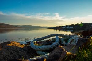 a boat sitting on the shore of a lake at Para Handy Cottage, Inveraray in Inveraray