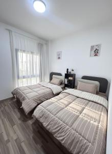 two beds in a bedroom with white walls and wood floors at Modern apartment Madinaty in New cairo