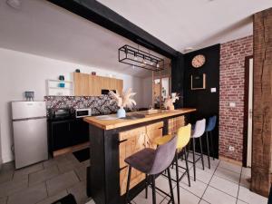 a kitchen with a bar with chairs and a refrigerator at Cosy atelier in Vierzon +13 photos