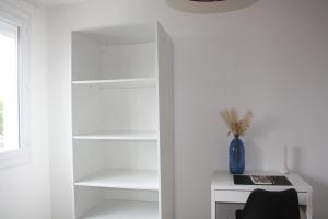 a room with white shelves and a desk and a window at Le cosy de Cholet près du PUY DUFOU in Cholet