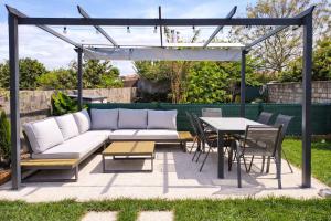 a patio with a white couch and a table and chairs at Herama Garden Guesthouse in Vila Nova de Gaia