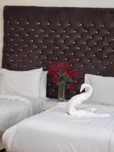 two beds with white sheets and a vase of red flowers at Dawn tawn velavet in Cairo