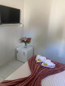 a room with a bed with towels and a tv at Quarto Real - Centro Histórico in Diamantina