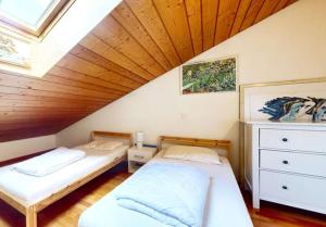 two beds in a room with a wooden ceiling at BluVilla in Malvaglia