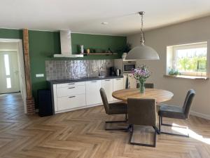 a kitchen with a wooden table and a kitchen with green walls at Vakantiewoning Op de Woerd in Aalten