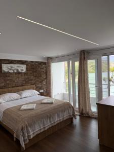 ein Schlafzimmer mit einem großen Bett und großen Fenstern in der Unterkunft Lundra in Gramsh