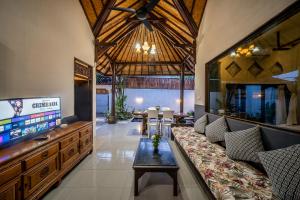 a living room with a couch and a flat screen tv at Villa Papat Seminyak in Seminyak