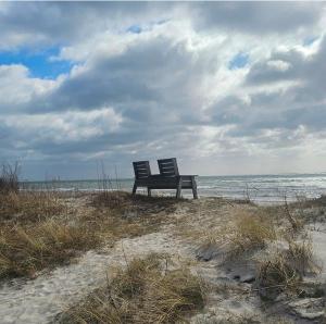 two chairs sitting on the beach near the ocean at Ocean Breeze next to the Beach in Beddinge Strand