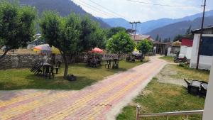 a brick walkway with tables and umbrellas in a park at Hotel Veerjeet Resorts in Doda