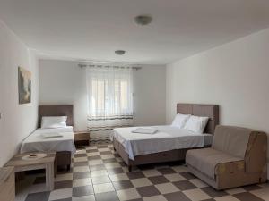 a bedroom with two beds and a couch and a chair at Guest House Ugljevarevic in Budva
