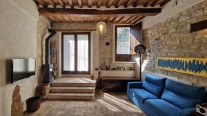 a living room with a blue couch and a stone wall at Domus Calzolari in Gubbio