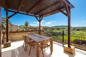 a patio with a wooden table and chairs on a balcony at Villayana Holiday Home in San Lawrenz