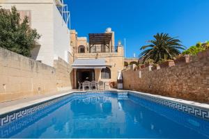 a swimming pool in front of a building with a house at Villayana Holiday Home in San Lawrenz