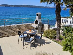 a table and chairs on a patio next to the water at Beach House Adria in Bibinje