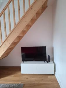 a flat screen tv on a white cabinet under a staircase at Escale cosy à Blois in Blois