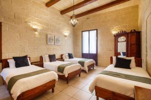 a room with three beds in a stone wall at Villayana Holiday Home in San Lawrenz +34 photos