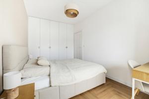 a white bedroom with a bed and a desk at Neon Apartments Centrum in Częstochowa