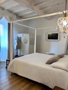a bedroom with a white bed and a chandelier at Palazzo Calderini in Castiglion Fiorentino