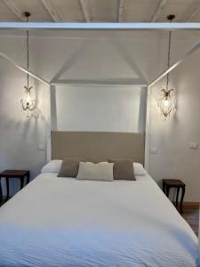 a bedroom with a large white bed with two lights at Palazzo Calderini in Castiglion Fiorentino