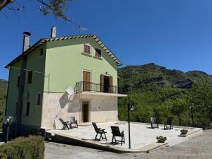 a green house with chairs in front of it at CASA DI BETTA Appartamento 3 Ascoli, Norcia, Monti Sibillini in Piana di Forcella