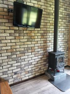 a fireplace with a tv on a brick wall at Olchowym Domek in Gostynin
