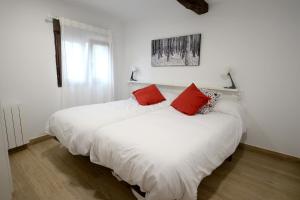 two beds in a white room with red pillows at Apartamentos California in Béjar