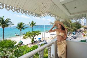 a woman standing on a balcony with a view of the beach at The Taksim Royal Beachfront Resort in Patong Beach +197 photos