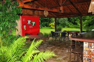 a patio with tables and chairs under a red booth at Eco Charme da Bodoquena in Bodoquena