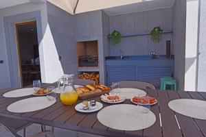 a wooden table with plates of food and orange juice at Villa Macedo in Ponta do Sol