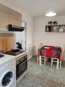 a small kitchen with a table and a washing machine at Petite maison dans le Morvan in Luzy