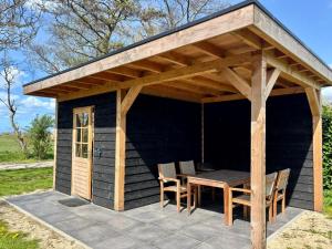 a wooden pavilion with a table and chairs on a patio at Waegen Uus in Wolphaartsdijk