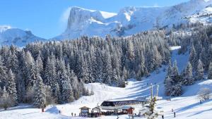 a ski lodge on a snowy mountain with snow covered trees at Le Cocon d'Aurouze in Le Dévoluy