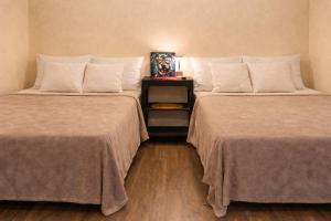 a hotel room with two beds and a nightstand between them at Los Cipreses Eco Hotel in Sonsonate +11 photos