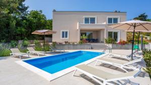 a villa with a swimming pool in front of a house at Casa Tijana by Villas Guide in Krk