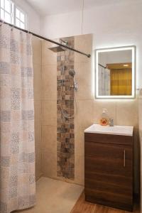 a bathroom with a shower with a sink and a mirror at Los Cipreses Eco Hotel in Sonsonate