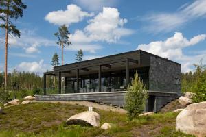 a black house on a hill with rocks at Luksushuvila yksityisellä SPA-alueella ja järvinäköalalla in Ähtäri