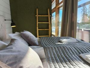 a bedroom with a bed with pillows and a ladder at Luksushuvila yksityisellä SPA-alueella ja järvinäköalalla in Ähtäri