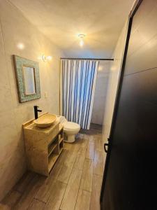 a bathroom with a toilet and a sink and a door at Yolcehuikalli - Loft Cuetzalan in Cuetzalán del Progreso