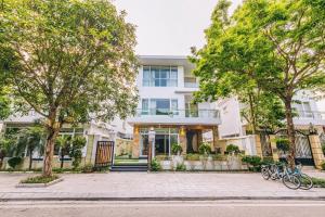 a white house with trees in front of it at Villa nt 48 FLC Thanh Hoá in Sầm Sơn