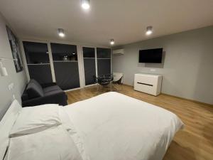 a bedroom with a white bed and a television at Słoneczna DWÓJKA Resort SPA in Gródek Nad Dunajcem