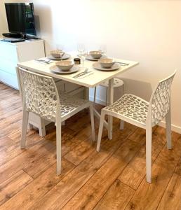 a white table and chairs with wine glasses on it at Charme et confort in Montévrain