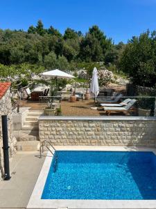 a swimming pool next to a patio with an umbrella at Marojica Apartments 2 in Cavtat