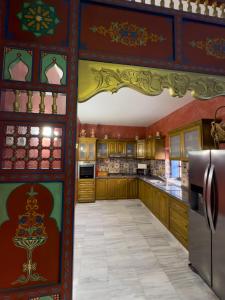a kitchen with red walls and wooden cabinets at Houch Ennejma in Al Ḩārah al Kabīrah